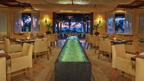 A hotel lobby with a central water feature, seating arrangements, and large windows with views of palm trees. - Splendid 5-bedroom ocean-view villa at The Four Seasons Punta Mita (Punta de Mita)