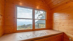 A wooden cabin with a bench by a large window offering a view of the mountains. - HAWKS RIDGE HIDEAWAY- Luxury Cabin & Great Get-Away! Amaazing view! (Bryson City)