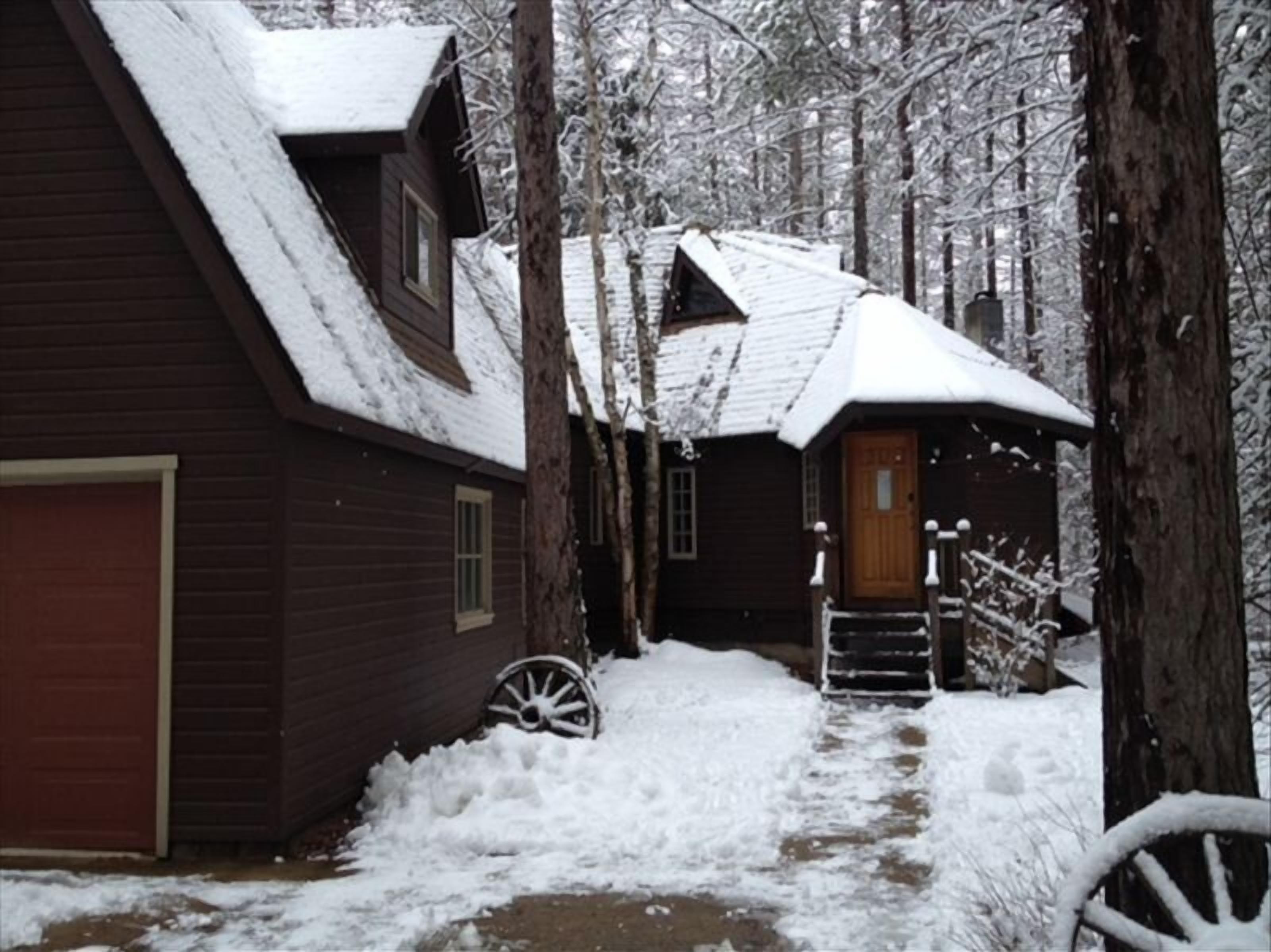 Una cabaña de madera con techo nevado y puerta de madera.