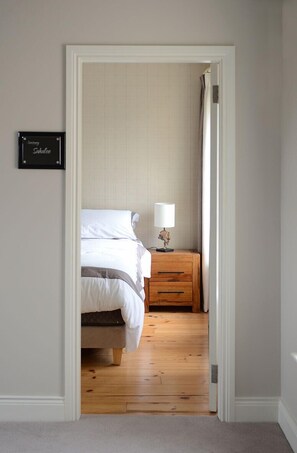 A bedroom with a bed, bedside table, and a lamp. - Custom Home for Golfers (Killarney)
