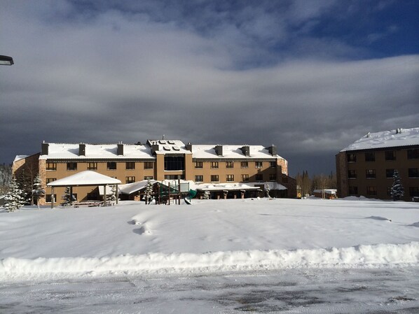 A large building with multiple windows and a flat roof, surrounded by snow-covered ground.
