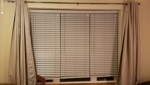 A room with a large window covered by horizontal blinds, a chair, and a small table. - Brian head Studio in 3.5 star Cedar Breaks Lodge - Sleeps 4 (Brian Head)