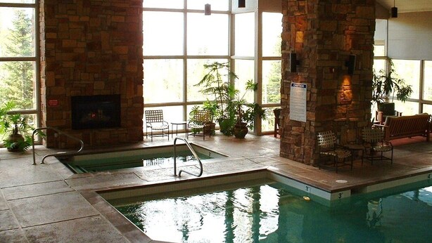An indoor swimming pool with stone walls, large windows, and seating areas. - Brian head Studio in 3.5 star Cedar Breaks Lodge - Sleeps 4 (Brian Head)