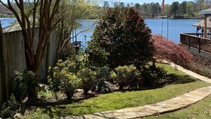 A residential property with a view of a lake, a wooden deck, and a fenced yard with various shrubs and trees. - Lake Hamilton Lakefront! Main Channel Large Decks & Boat Dock! Spectacular View! (Hot Springs)