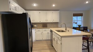 A kitchen with white cabinets, a black refrigerator, a sink, and a window with blinds. - Lake Hamilton Lakefront! Main Channel Large Decks & Boat Dock! Spectacular View! (Hot Springs)