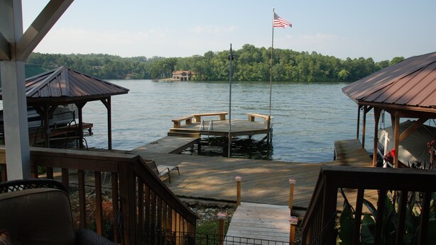 A wooden dock extending into a lake with a gazebo and a flagpole with an American flag. - Lake Hamilton Lakefront! Main Channel Large Decks & Boat Dock! Spectacular View! (Hot Springs)