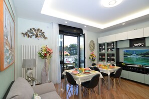 A modern living room with a dining area, a TV, and a view of the outdoors. - Caserta Deluxe (Caserta)