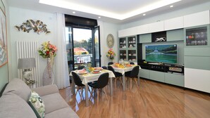 Una sala de estar moderna con comedor, televisor y vista a un edificio.