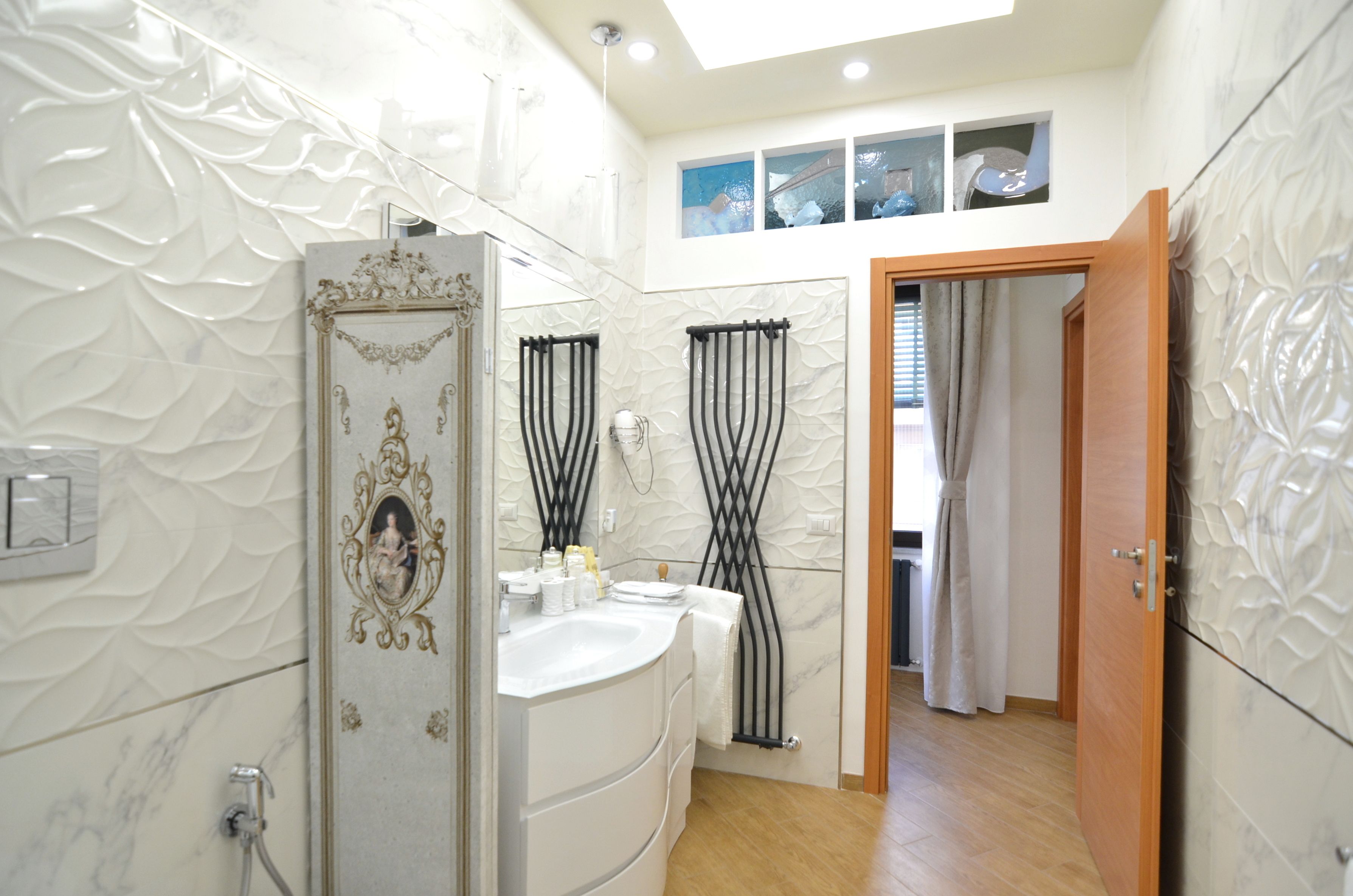 A bathroom with a white vanity, a shower with black curtains, and a wooden door leading to another room.
