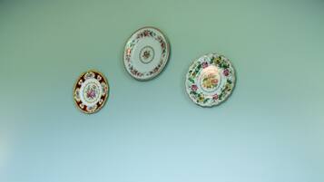 A bed with floral bedding and three decorative plates on the wall.