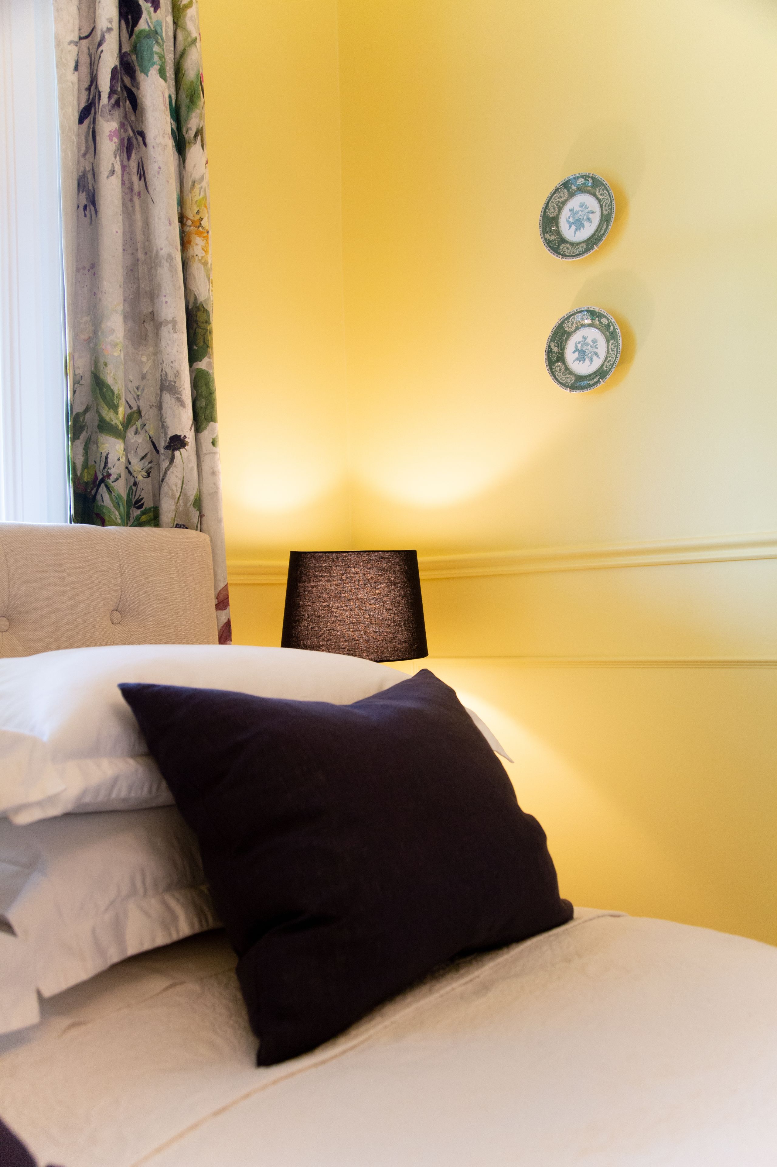 A bed with pillows, a lamp, and two wall plates.
