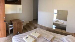 A small, compact room with a bed, a desk, a chair, a TV mounted on the wall, and a mirror reflecting the bed. - Hotel Butantã (São Paulo)