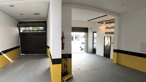 A hallway with a closed gate, a fire extinguisher, and a view of the street outside. - Hotel Butantã (São Paulo)