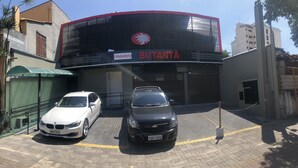 A building with a sign reading "Hospedaria BUTANTÃ" and two cars parked in front. - Hotel Butantã (São Paulo)