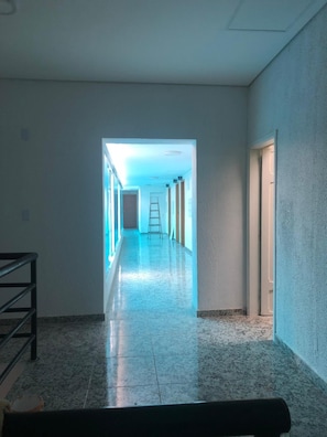 A corridor with a tiled floor, a metal railing on one side, and a ladder in the distance. - Hotel Butantã (São Paulo)