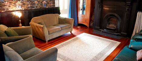 A cozy living room with a fireplace, two sofas, a rug, and wooden flooring.