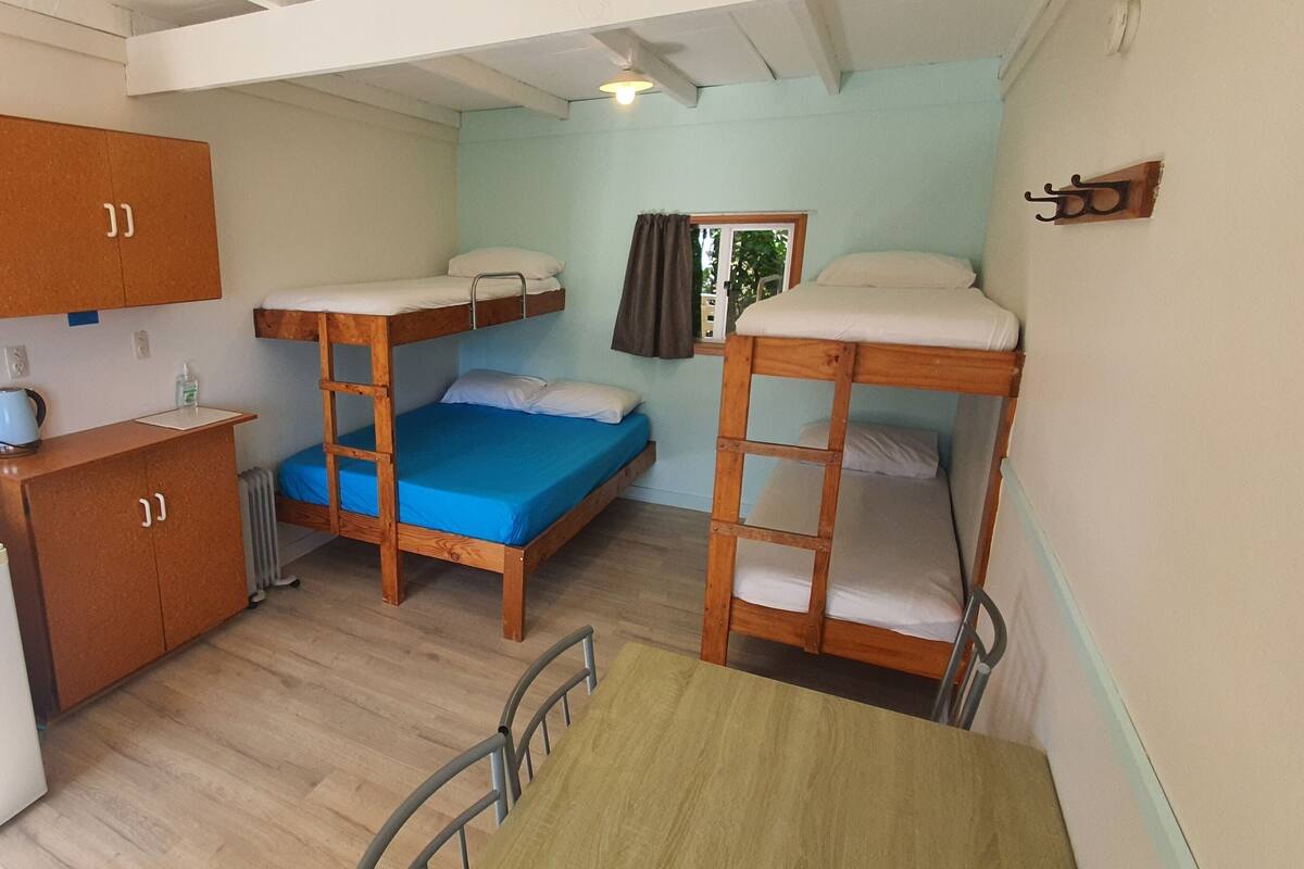 A compact room with bunk beds, a small kitchenette, a mirror, and a table.