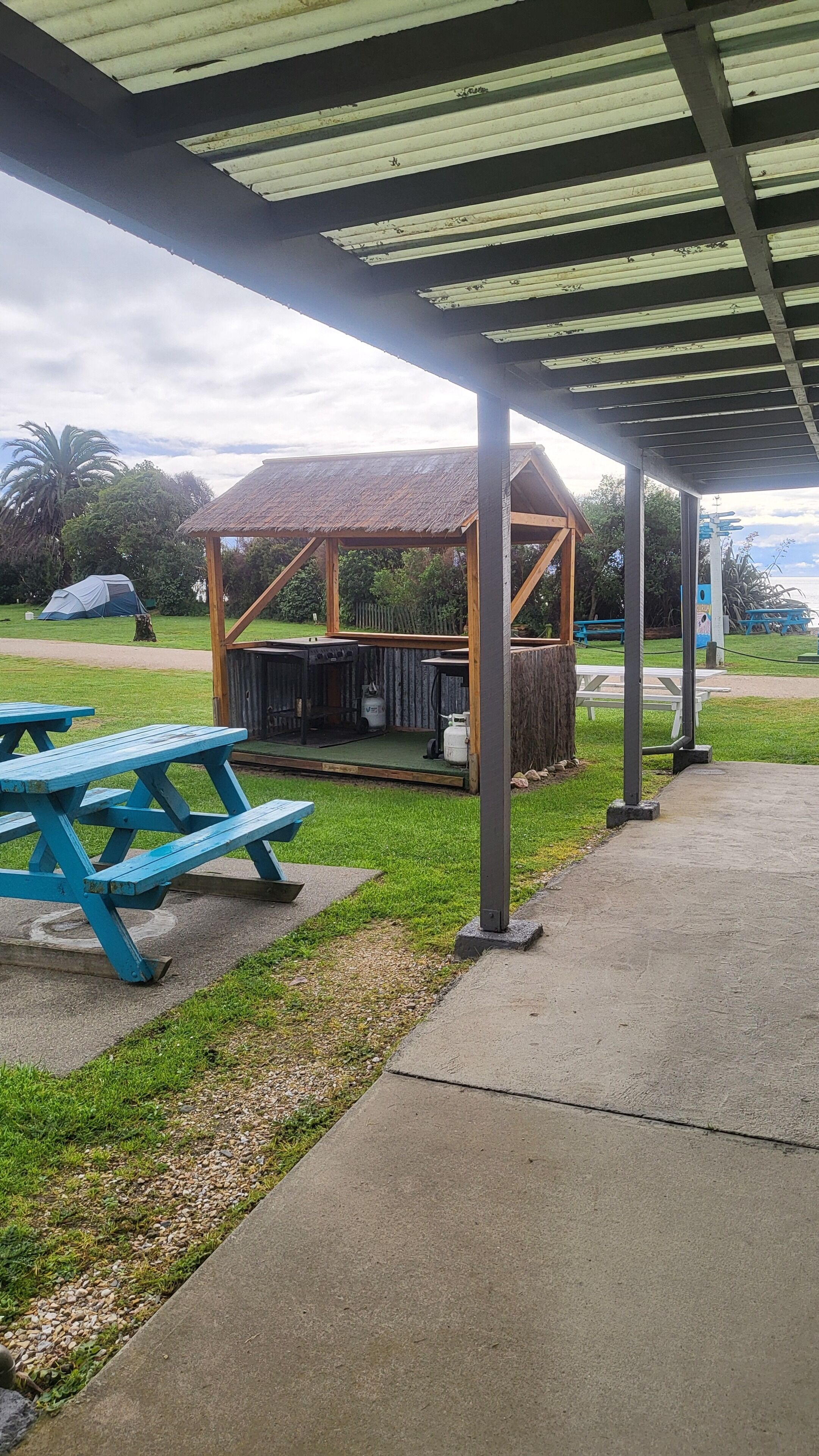 A covered picnic area with a grill, picnic tables, and a small shelter.