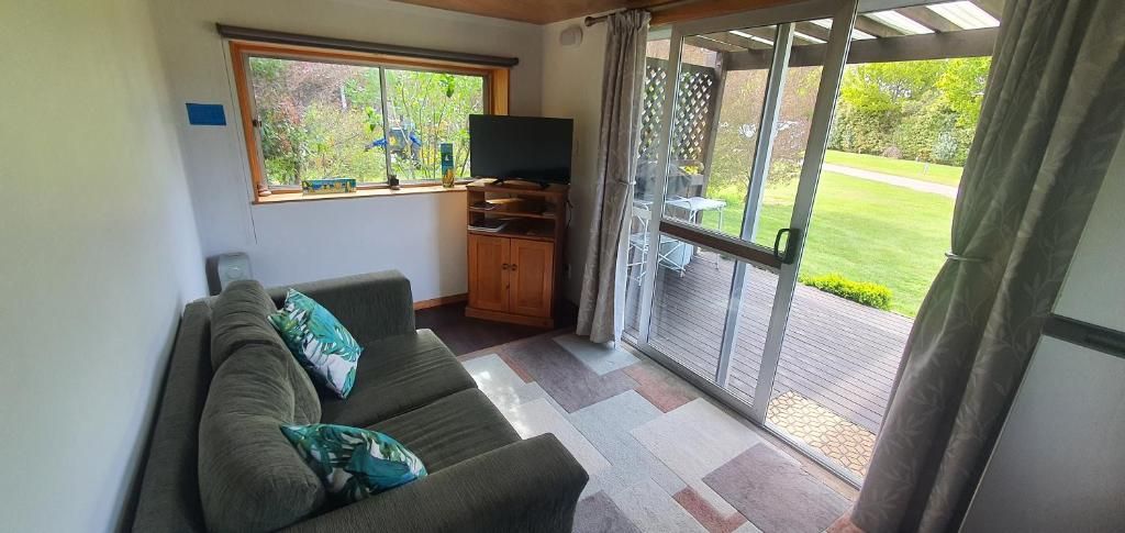 A living room with a sofa, a television, and a sliding glass door leading to an outdoor area.