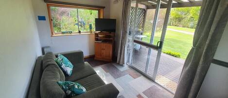 A living room with a sofa, a television, and a sliding glass door leading to an outdoor area.