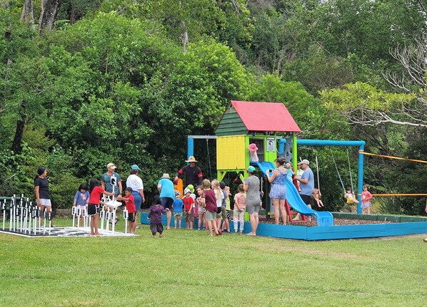 A playground with a slide and climbing structures, surrounded by greenery. - Golden Bay Holiday Park (Parapara)