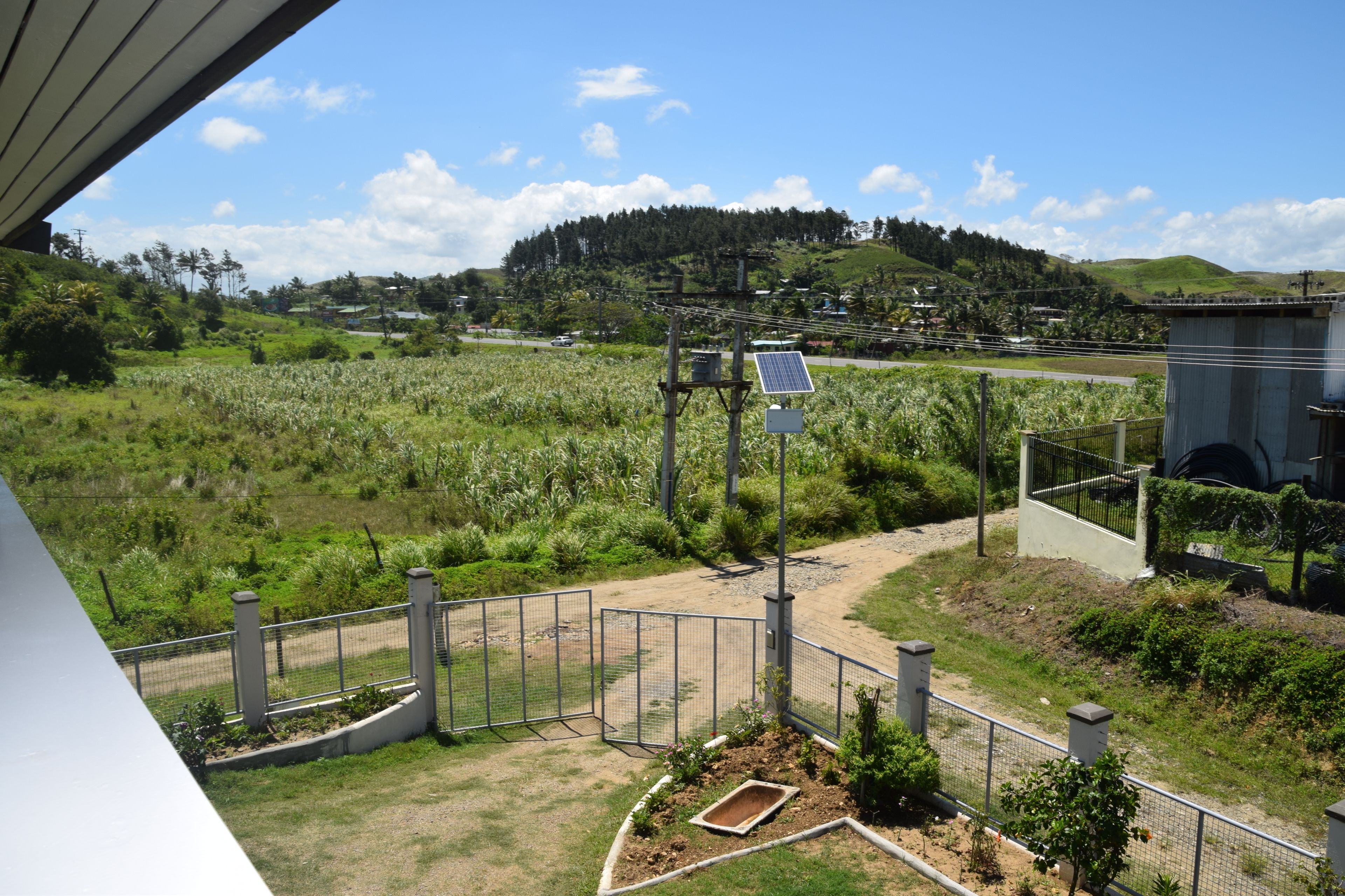 Un espace extérieur clos, doté d’un panneau solaire, d’un petit jardin et offrant une vue sur un paysage vallonné.