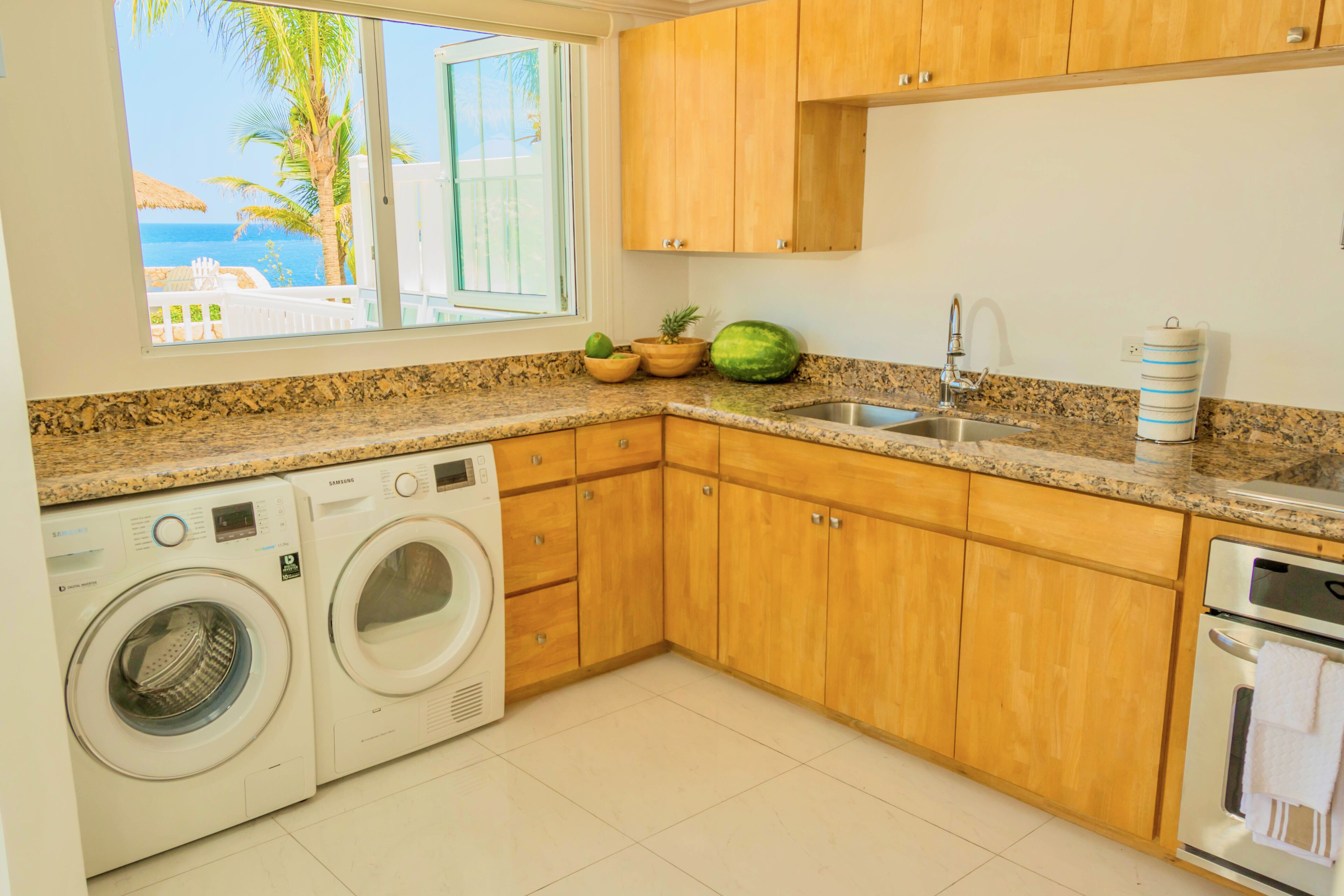 A kitchen with wooden cabinets, a granite countertop, a built-in oven, and a washing machine.