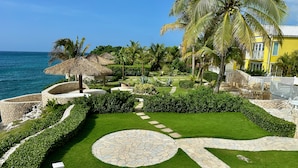 A well-maintained garden with a stone pathway, palm trees, and a view of the ocean. - Stunning Ocean View (Negril)