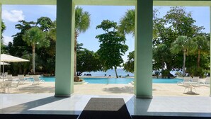 A pool area with lounge chairs and a view of the sea. - Stunning Ocean View (Negril)