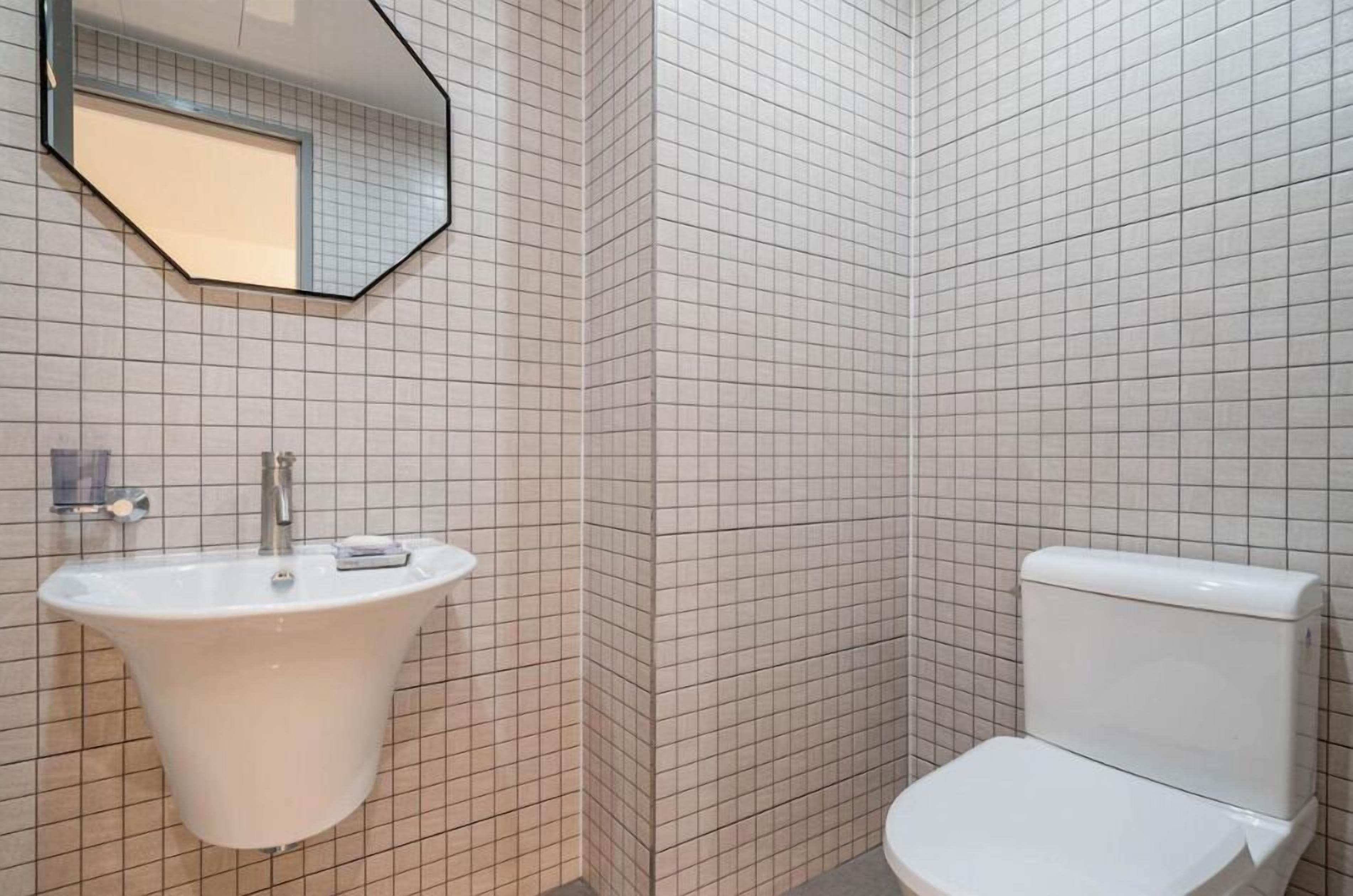 Une salle de bain avec un lavabo blanc, des toilettes et un miroir au mur.