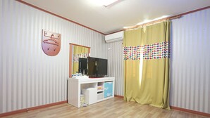 A room with a white entertainment unit, a flat-screen TV, and a yellow curtain with a polka dot pattern. - Jeongdongjin Motel (Gangneung)