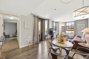 A spacious living area with a dining table, chairs, a sofa, and a TV.