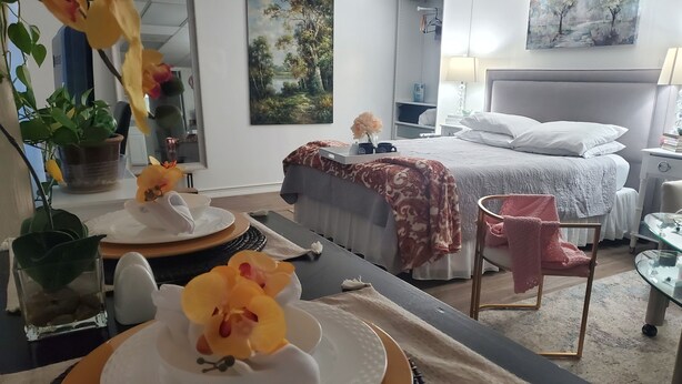 A hotel room with a bed, bedside table, lamp, and a painting on the wall.