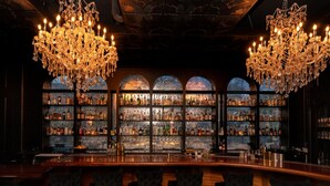 Un bar agrémenté de lustres décoratifs, avec un comptoir et des étagères remplies de bouteilles.