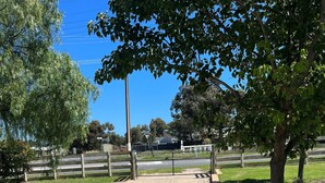 A gravel path leading to a fenced area with a tree on the right. - THE SHACK - GOOLWA CENTRAL (Goolwa)