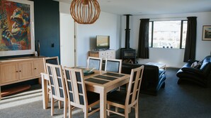 Un soggiorno moderno con un tavolo da pranzo in legno, sedie, un divano, un caminetto e un grande quadro appeso al muro.