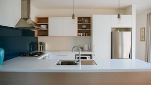 Una cucina moderna con isola centrale, elettrodomestici in acciaio inossidabile e illuminazione a sospensione.