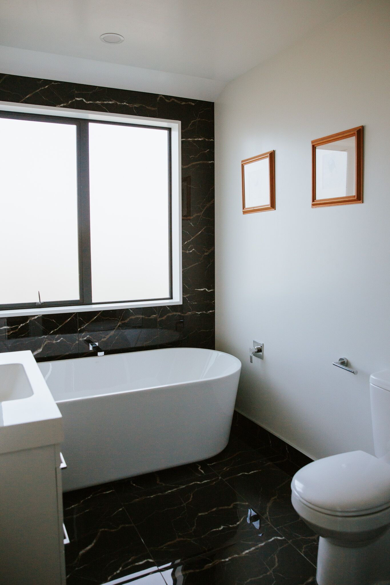 A modern bathroom with a freestanding bathtub, a toilet, and a window.