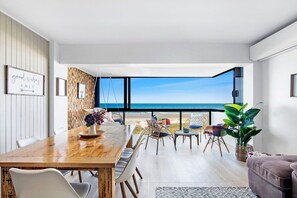 Enjoy ocean views from the large window in this spacious living area, featuring a dining table and comfortable seating.