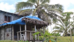 A rustic house with a thatched roof and a blue tarp. - Tanna Ikamir Bungalows and Accomodations (Tanna Island)