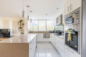 A modern kitchen with a large island, stainless steel appliances, and a view of the outdoors.