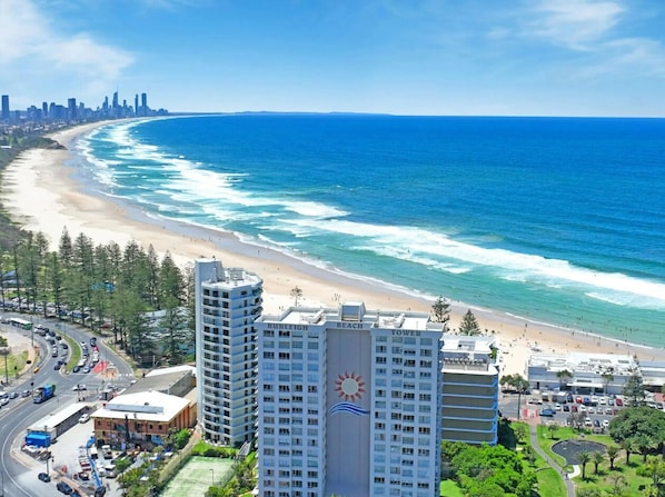 A coastal cityscape with a beach, high-rise buildings, and a clear sky.