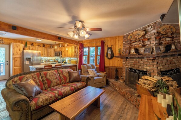 A cozy living room with a sofa, a coffee table, and a fireplace. - Arrowhead, A/C, Private Jacuzzi, Huge Backyard, 65" TV, Fully Stocked, Dogs OK. (Twin Peaks)