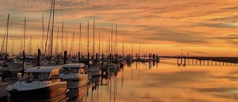 Un puerto deportivo con varias embarcaciones amarradas a muelles de madera al atardecer.