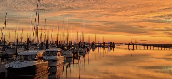 Un puerto deportivo con varias embarcaciones amarradas a muelles de madera al atardecer.