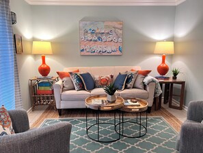 A living room with a sofa, two side tables, a coffee table, and a painting on the wall.