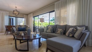 Ein modernes Wohnzimmer mit einem grauen Sofa, einem runden Couchtisch und einem gemusterten Sessel.