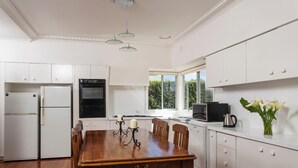 Une cuisine moderne avec des meubles blancs, une table à manger en bois et une fenêtre donnant sur un paysage verdoyant.