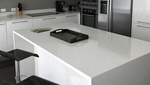 Een moderne keuken met witte kastjes, roestvrijstalen apparatuur en hanglampen.