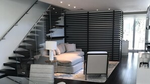 Een modern interieur met een glazen trap, een bank, een eettafel met stoelen en een keukenhoek.